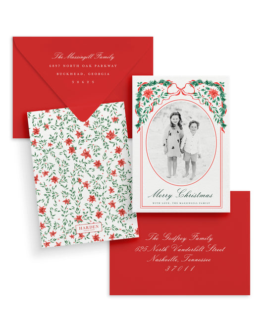 Christmas card set with floral design, photo of two children, and red envelope.